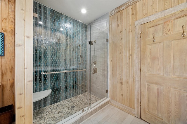 full bath featuring wood walls, wood finished floors, recessed lighting, and a shower stall