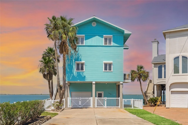 coastal home featuring a gate, concrete driveway, and fence private yard