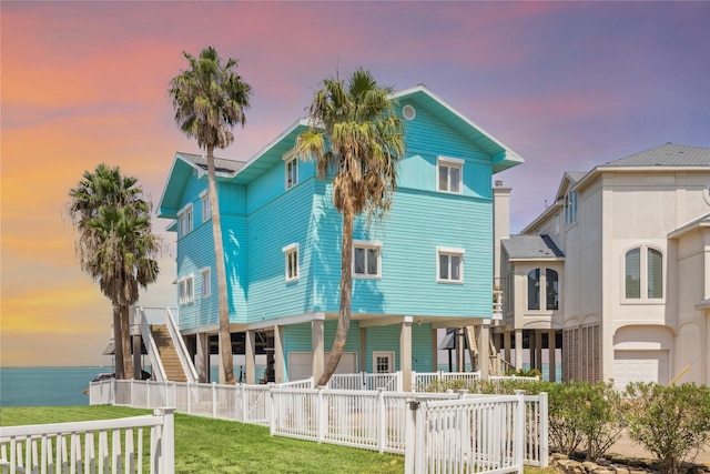 rear view of house featuring stairs, a yard, a water view, fence private yard, and a porch