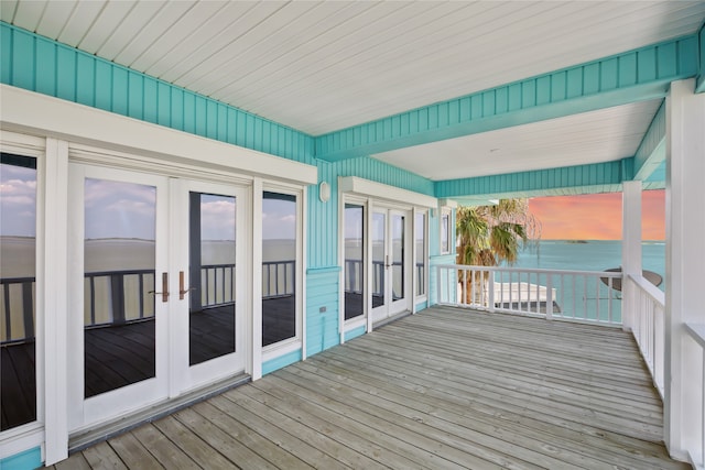 unfurnished sunroom featuring a water view, french doors, and plenty of natural light