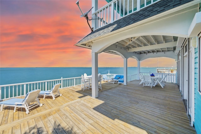 deck at dusk featuring a water view and a gazebo