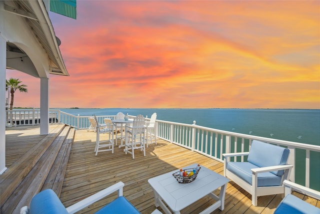 deck at dusk featuring a water view