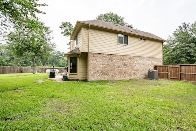 rear view of house with a lawn and central AC