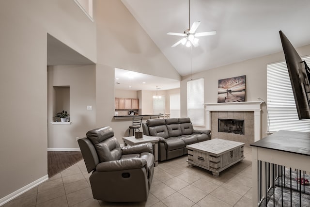 living room featuring high vaulted ceiling, ceiling fan, light tile patterned floors, and a tile fireplace