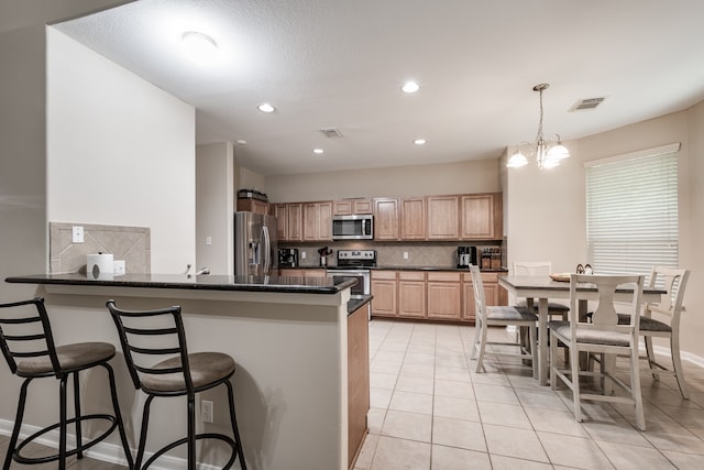 kitchen with decorative light fixtures, a notable chandelier, appliances with stainless steel finishes, kitchen peninsula, and decorative backsplash