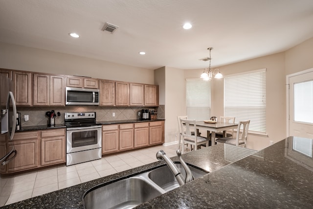 kitchen with a chandelier, backsplash, light tile patterned floors, decorative light fixtures, and stainless steel appliances