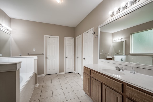 bathroom with tile patterned flooring, tiled bath, and vanity