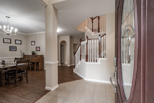 entryway with a textured ceiling, crown molding, a notable chandelier, and light hardwood / wood-style floors