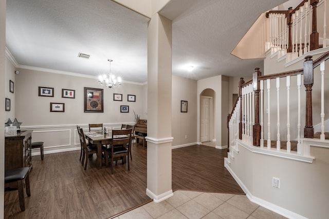 dining room with light wood-type flooring, crown molding, an inviting chandelier, and a textured ceiling