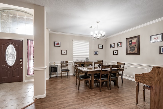 dining room with ornamental molding, a textured ceiling, hardwood / wood-style floors, and an inviting chandelier