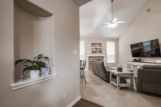 living room with a tiled fireplace, lofted ceiling, light tile patterned flooring, and ceiling fan