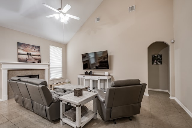 living room featuring a fireplace, high vaulted ceiling, light tile patterned flooring, and ceiling fan