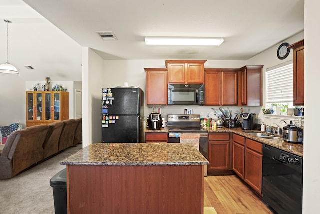 kitchen with sink, dark stone countertops, light carpet, pendant lighting, and black appliances