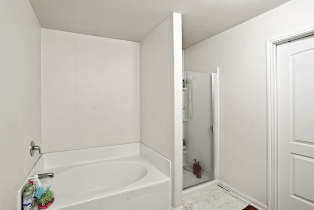 bathroom with a textured ceiling and independent shower and bath