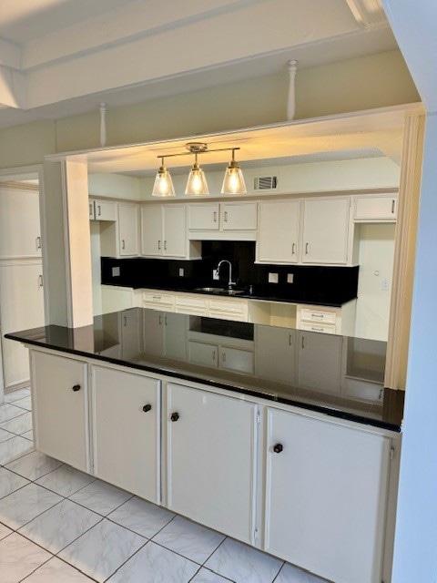 kitchen with light tile patterned floors, decorative light fixtures, decorative backsplash, and white cabinets