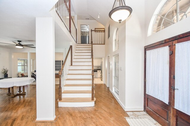 entrance foyer featuring ceiling fan, light wood-type flooring, french doors, and a towering ceiling