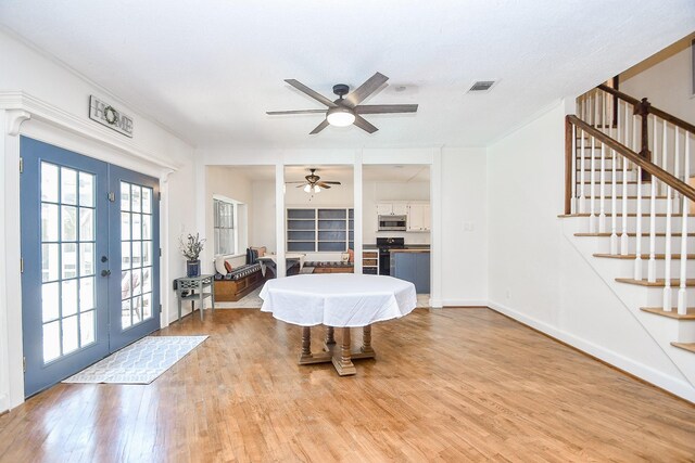 interior space featuring light wood-type flooring, ornamental molding, french doors, and ceiling fan