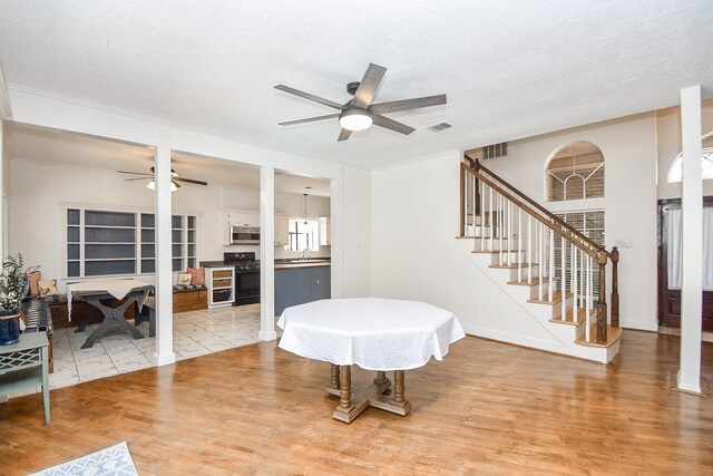 dining room with ceiling fan, light hardwood / wood-style floors, a textured ceiling, and sink