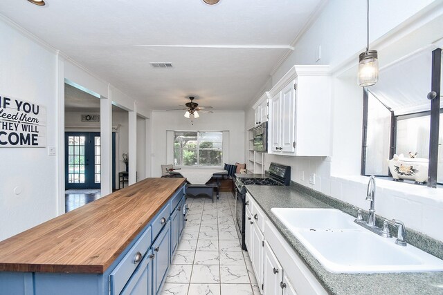 kitchen with black stove, hanging light fixtures, white cabinets, blue cabinets, and sink