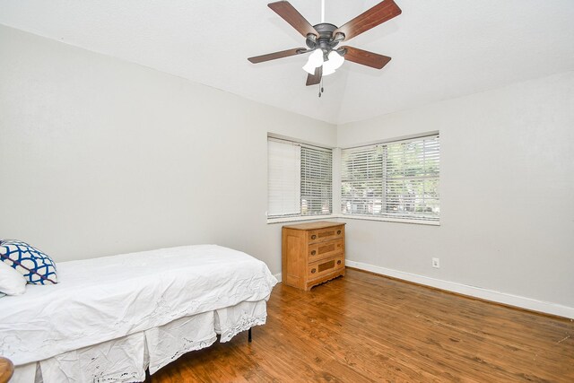 bedroom with ceiling fan, dark hardwood / wood-style floors, and vaulted ceiling