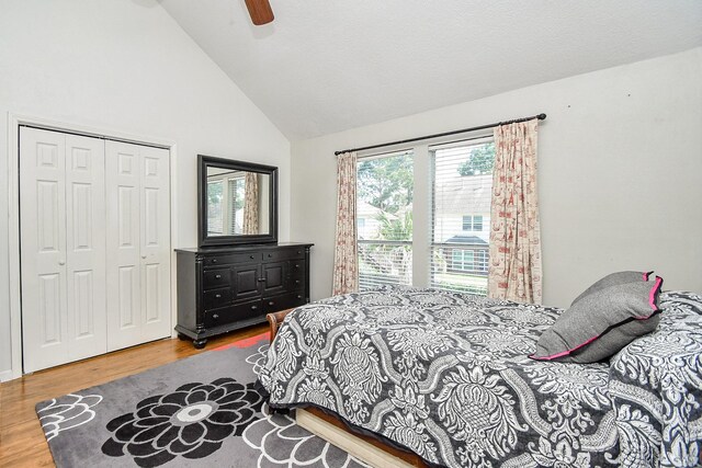 bedroom featuring ceiling fan, high vaulted ceiling, wood-type flooring, and a closet