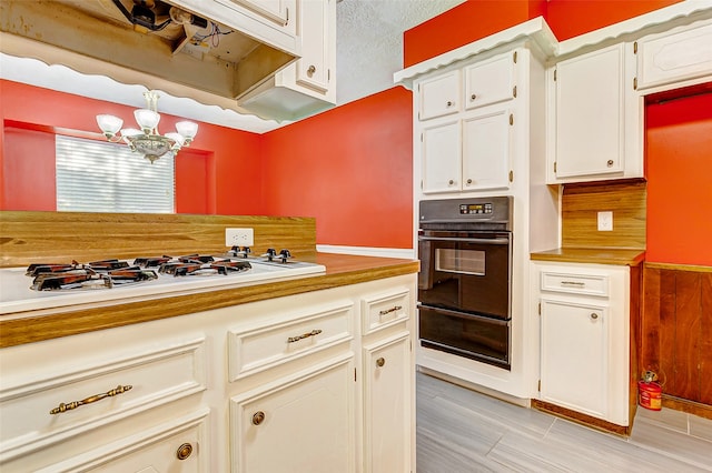 kitchen with light tile patterned flooring, backsplash, an inviting chandelier, double oven, and white gas cooktop