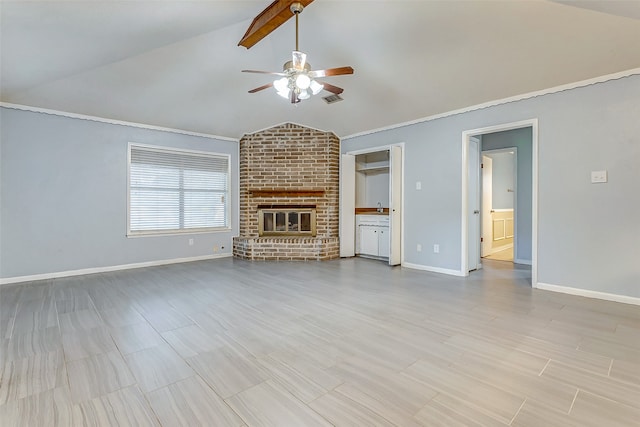 unfurnished living room with ceiling fan, brick wall, sink, a fireplace, and lofted ceiling with beams