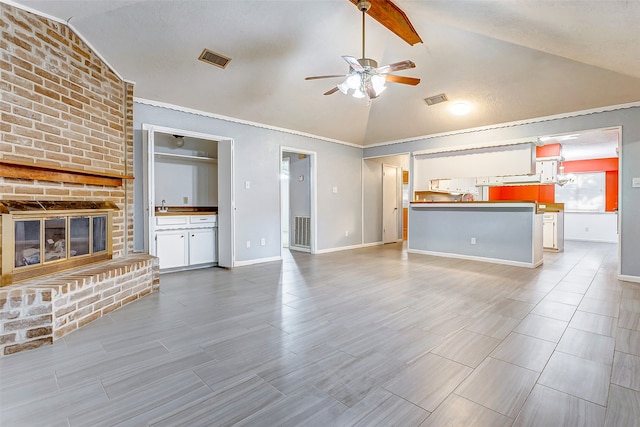 unfurnished living room with ceiling fan, brick wall, a brick fireplace, and lofted ceiling