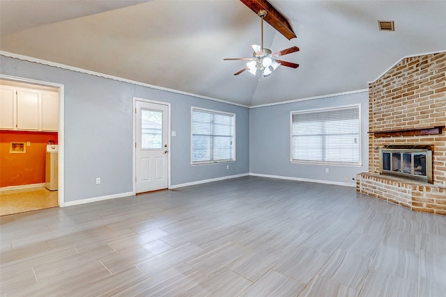 unfurnished living room featuring brick wall, washer / clothes dryer, vaulted ceiling with beams, ceiling fan, and a brick fireplace