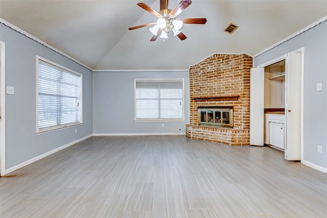 unfurnished living room with vaulted ceiling, a healthy amount of sunlight, brick wall, and a fireplace