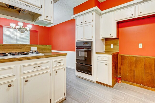 kitchen with a chandelier, double oven, white gas cooktop, white cabinetry, and light tile patterned flooring