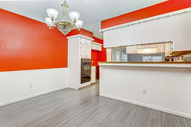 kitchen with double oven, kitchen peninsula, and an inviting chandelier