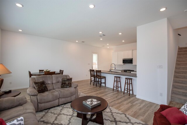 living room featuring sink and light hardwood / wood-style flooring