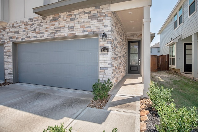 exterior space with stone siding, fence, and concrete driveway