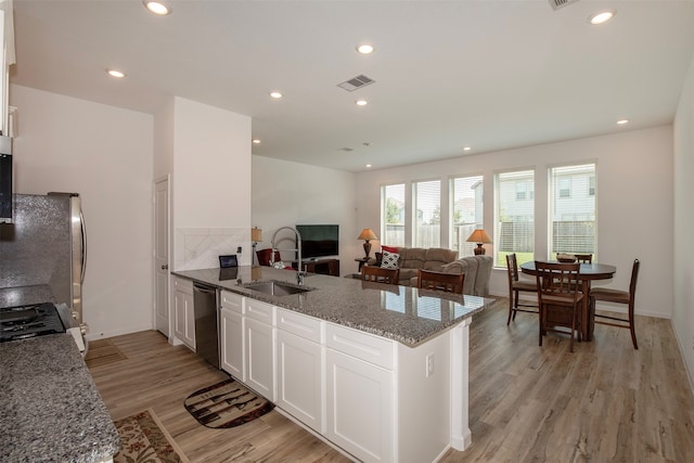 kitchen with stone counters, kitchen peninsula, sink, appliances with stainless steel finishes, and white cabinets