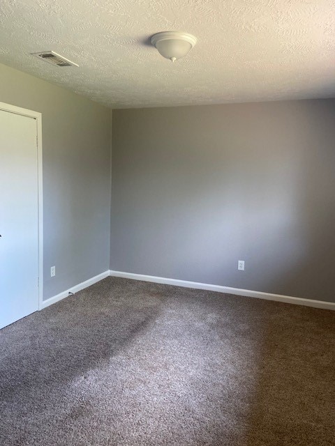 carpeted empty room with a textured ceiling