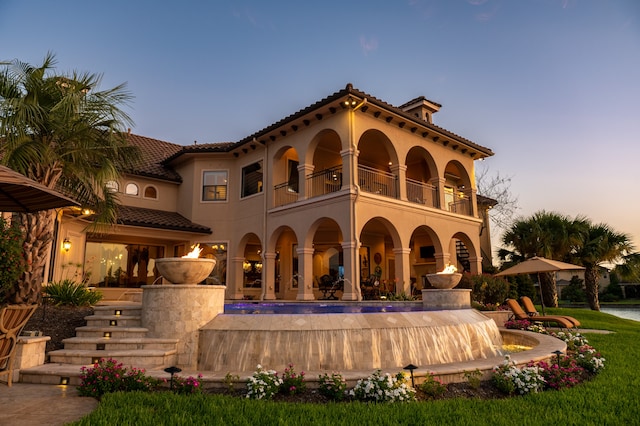 back house at dusk with a balcony