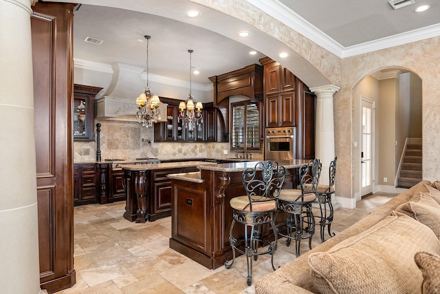 bar with visible vents, oven, ornamental molding, an inviting chandelier, and arched walkways