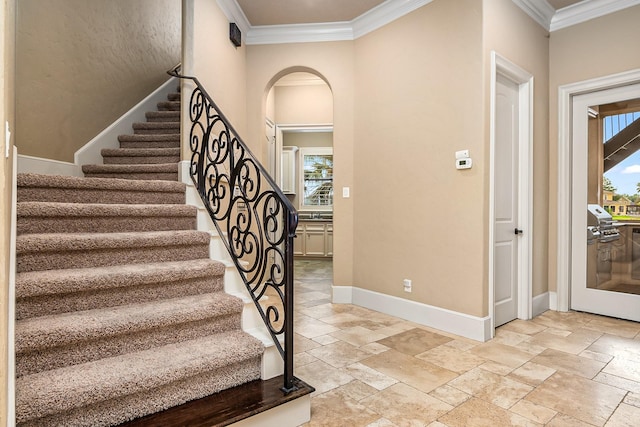 stairway with baseboards, arched walkways, stone tile flooring, and crown molding