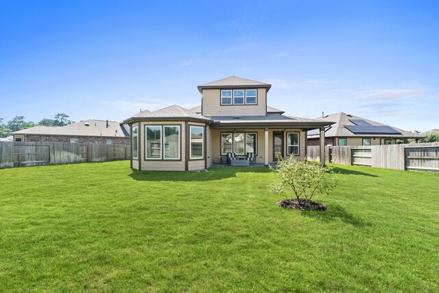 back of house featuring a lawn and solar panels