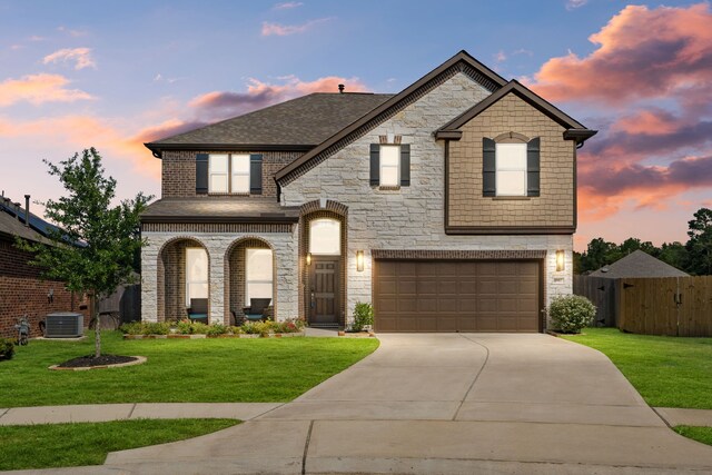 view of front facade with a garage, a yard, and central AC