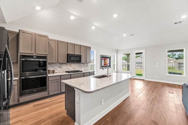 kitchen featuring vaulted ceiling, sink, light hardwood / wood-style flooring, and black appliances