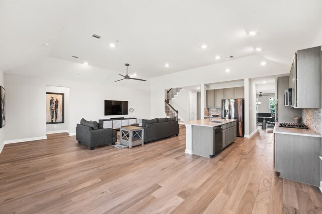 kitchen featuring backsplash, light hardwood / wood-style flooring, a kitchen island with sink, gray cabinetry, and ceiling fan