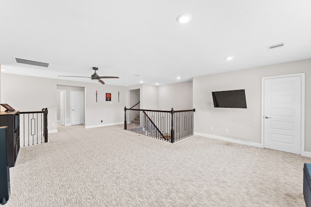 basement featuring ceiling fan and light colored carpet