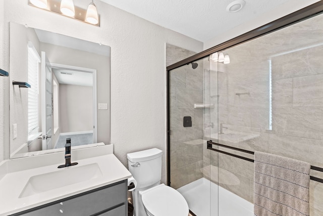 bathroom featuring toilet, a textured ceiling, a shower with shower door, and vanity