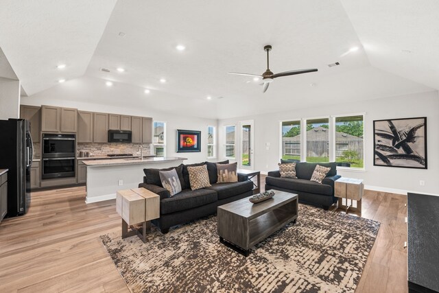 living room featuring ceiling fan, light wood-type flooring, and lofted ceiling