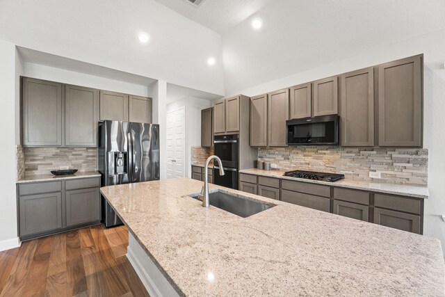 kitchen featuring dark hardwood / wood-style flooring, black appliances, and backsplash