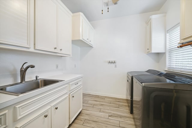 laundry area featuring washer and clothes dryer, cabinets, light wood-type flooring, and sink