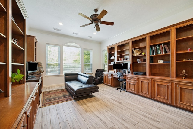 office area with ceiling fan, built in desk, a textured ceiling, light wood-type flooring, and ornamental molding