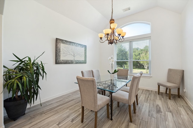 dining space with light wood-type flooring, lofted ceiling, a wealth of natural light, and an inviting chandelier